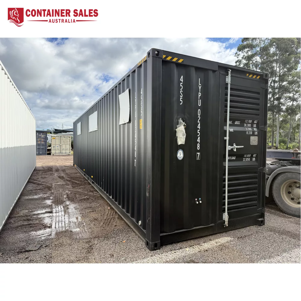 40ft High Cube Accommodation Container Home 2 Black shipping container in a gravel yard with serial numbers on the door, under a cloudy sky.