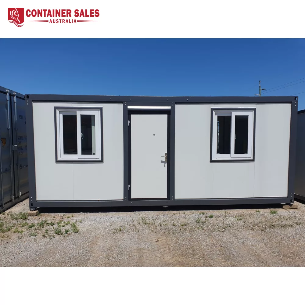 6m 2-Room Accommodation Unit (Type C) 1 Front view of a grey modular container with two white-framed windows and a central door on a gravel lot.