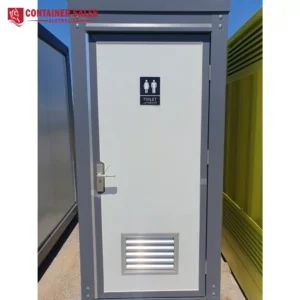 Outdoor portable toilet cabin with a vent at the bottom, a door handle, and a sign showing male and female figures with the word 'TOILET' on the door; metal frame and a blue sky in the background.